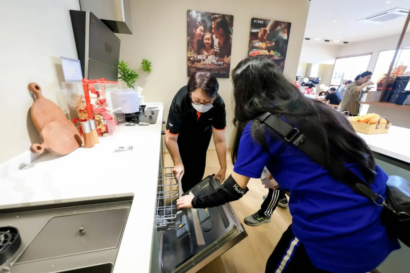 A Cabchen team member demonstrating a built-in Fotile appliance to a visitor at the showroom